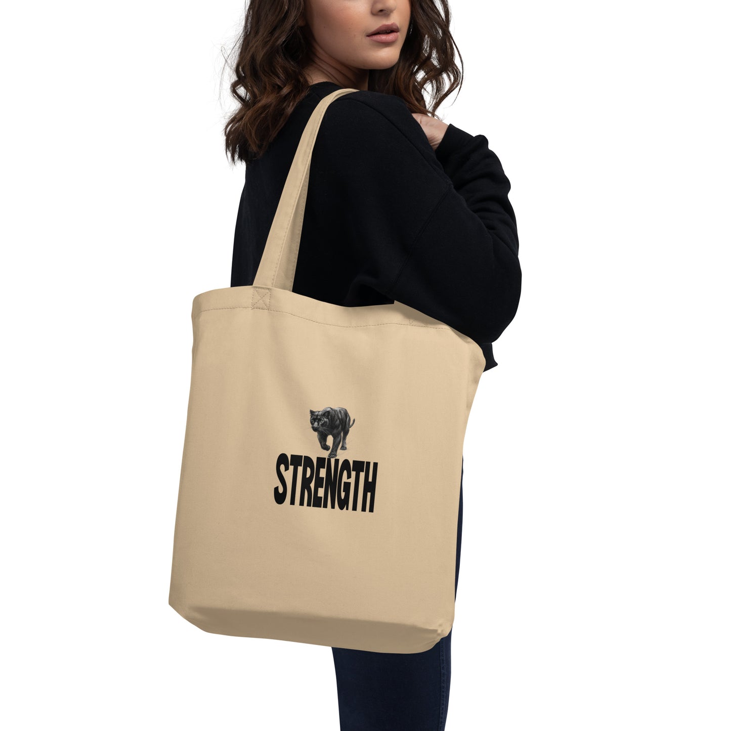 Person carrying an organic cotton tote bag featuring a black panther and the word "STRENGTH".