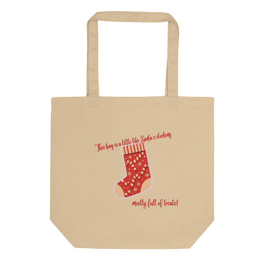 A beige canvas tote bag with a red Christmas stocking graphic and the text 'This bag is a little like Santa's stocking' and 'mostly full of treats!' on a plain white background.