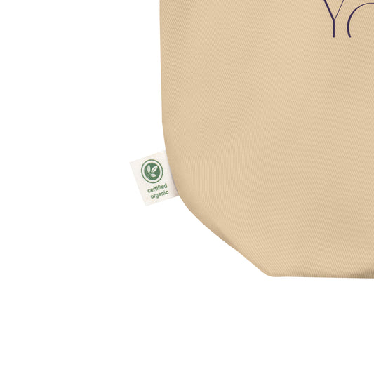 Beige tote bag with a green organic certification label on a white background