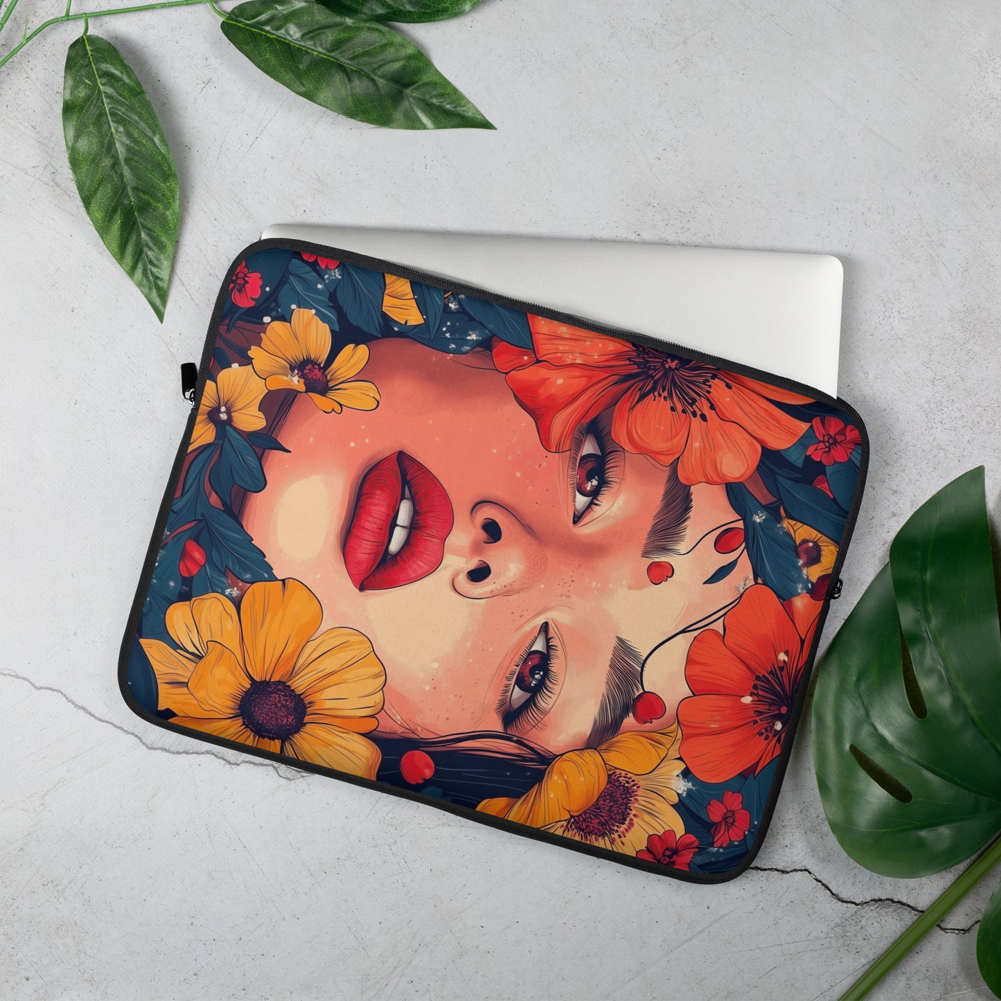 Laptop sleeve with floral and face design on a light gray surface with green leaves by Sweet and Savage.