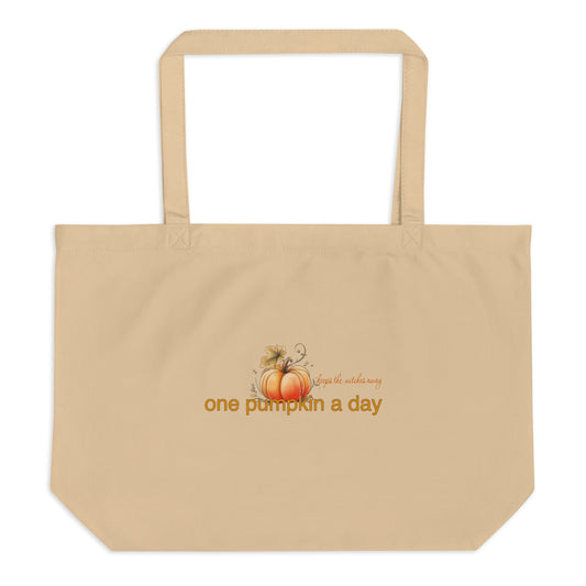 A beige canvas tote bag with two shoulder straps, featuring a small autumn graphic of pumpkins and the text 'One pumpkin a day, keeps the witches away' printed on the front, shown against a plain white background.