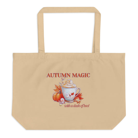 A beige canvas tote bag with a printed autumn-themed graphic on the front. The graphic features the text 'AUTUMN MAGIC with a dash of boo!' above an illustration of a white mug with a ghost face by Sweet & Savage, surrounded by orange pumpkin and red-orange autumn leaves.