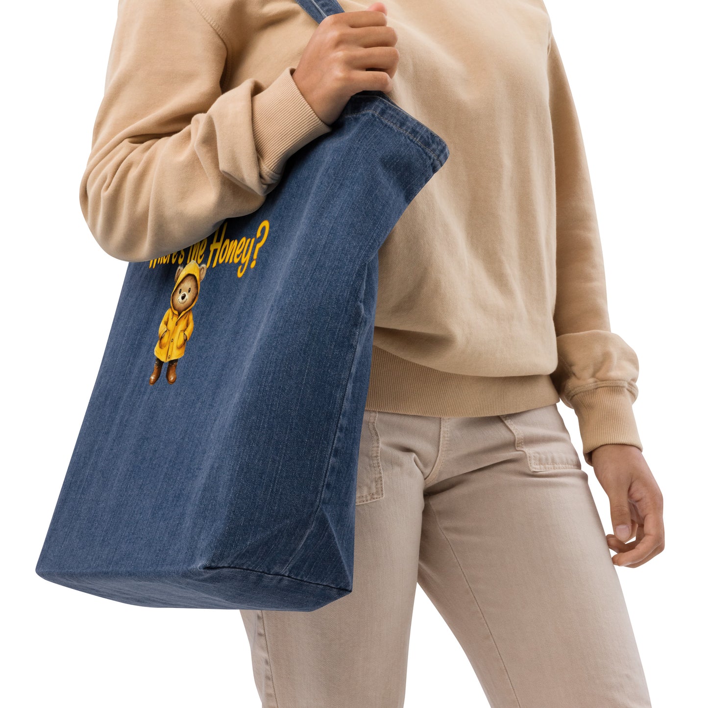 Person holding a an organic denim tote bag with a bear illustration and text on a white background