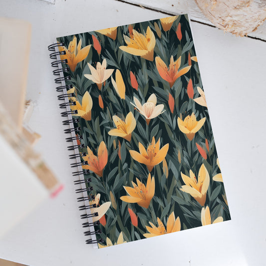 A5 spiral dotted notebook with a bold black and yellow tiger lily floral pattern on the cover, styled on a desk.
