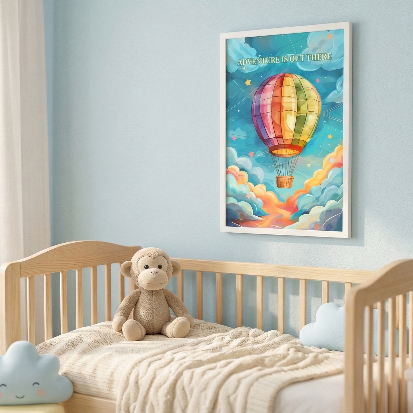 Lifestyle mockup of a framed 'Adventure is out there' hot air balloon poster in a bright, modern nursery. The white-framed poster is hung over a wooden crib with linen curtains, a knitted pouf, and a plush monkey toy, all bathed in soft natural light.