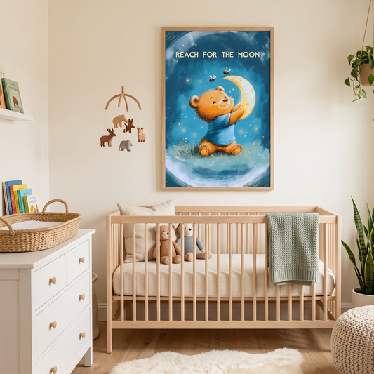 A framed wall art print featuring a cartoon teddy bear reaching for a crescent moon, hung above a light wood crib in a styled nursery room with a white dresser, mobile, rug, and plant.