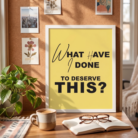 Framed poster with quote 'What have I done to deserve this? on yellow background on a desk with coffee and glasses. 