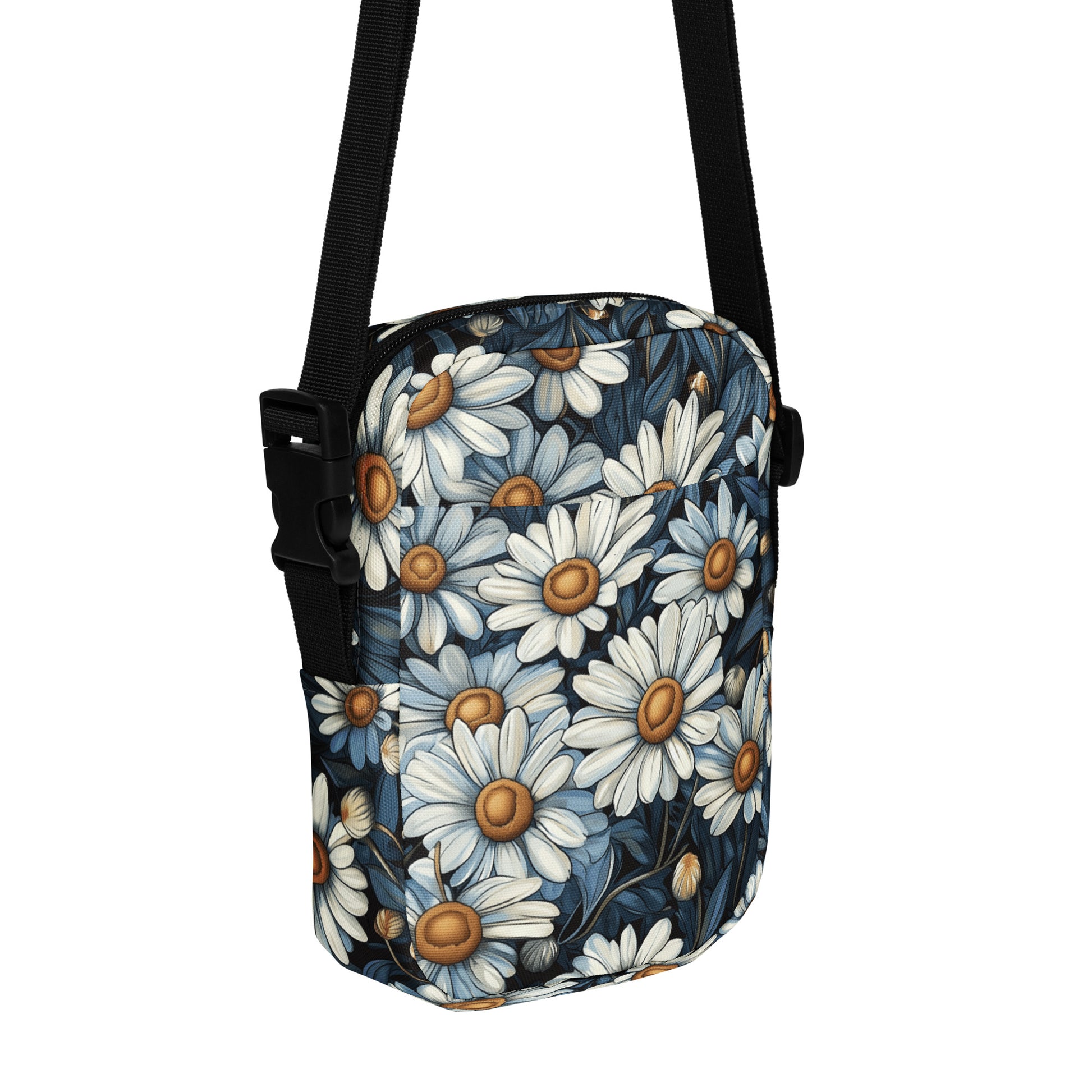 Crossbody bag with daisy floral pattern with a black strap on a white background. 