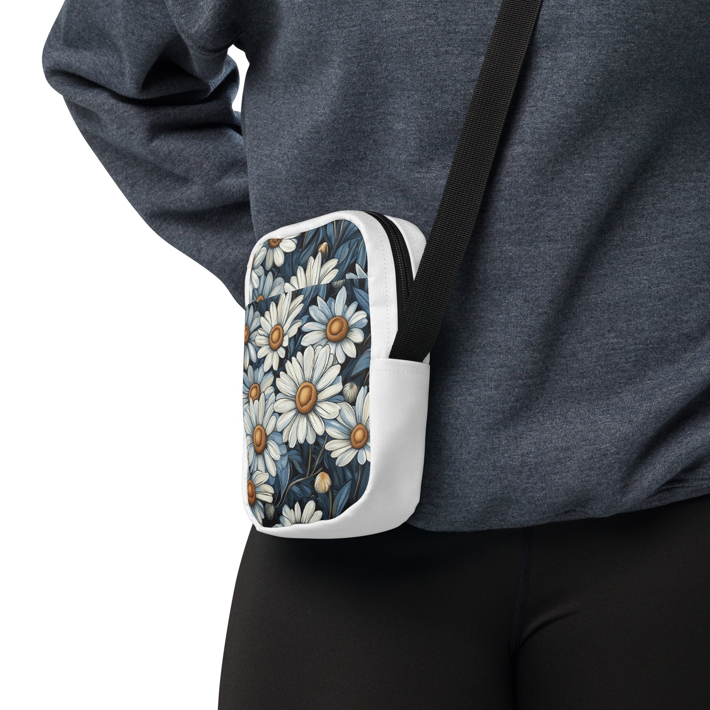 A person wearing a white utility crossbody bag with a blue and white daisy floral pattern.