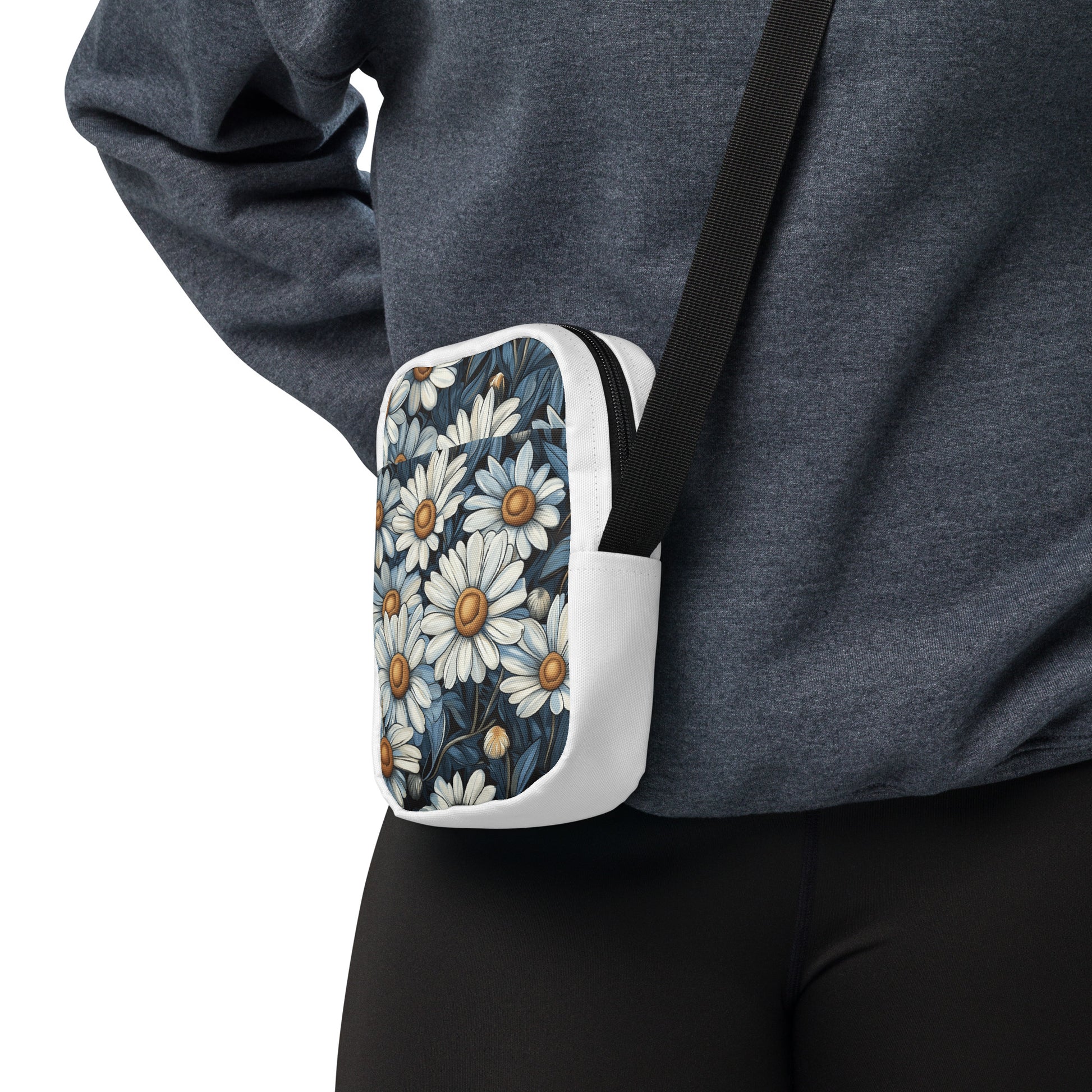 A person wearing a white utility crossbody bag with a blue and white daisy floral pattern.