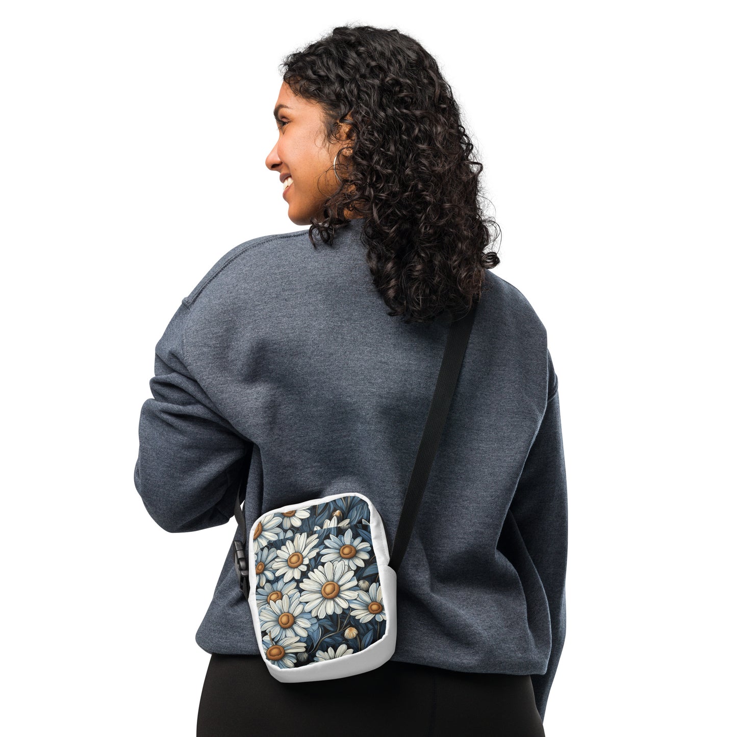 A person wearing a white utility crossbody bag with a blue and white daisy floral pattern.