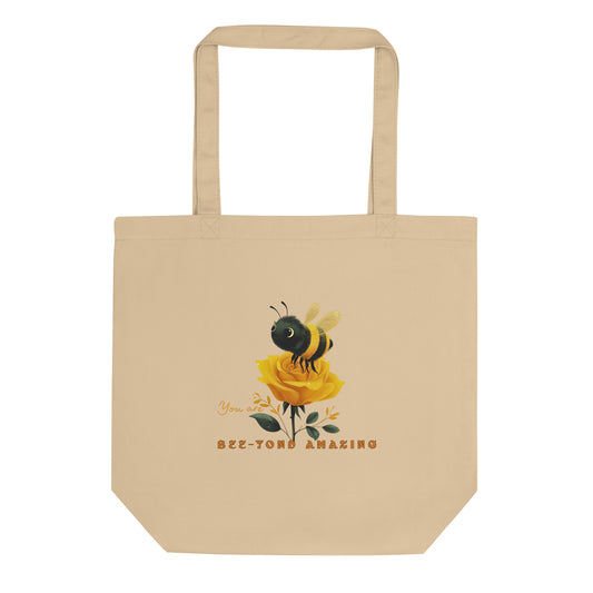 Beige eco tote bag with a bee and rose yellow rose design with the words 'You are Bee-yond amazing' on a white background. 