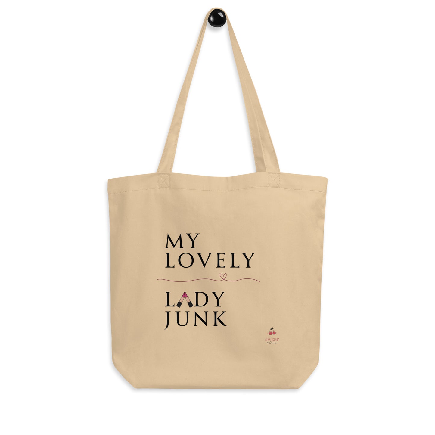 A beige canvas tote bag with black printed text reading 'MY LOVELY LADY JUNK' and a small pink heart, hanging against a plain white background.