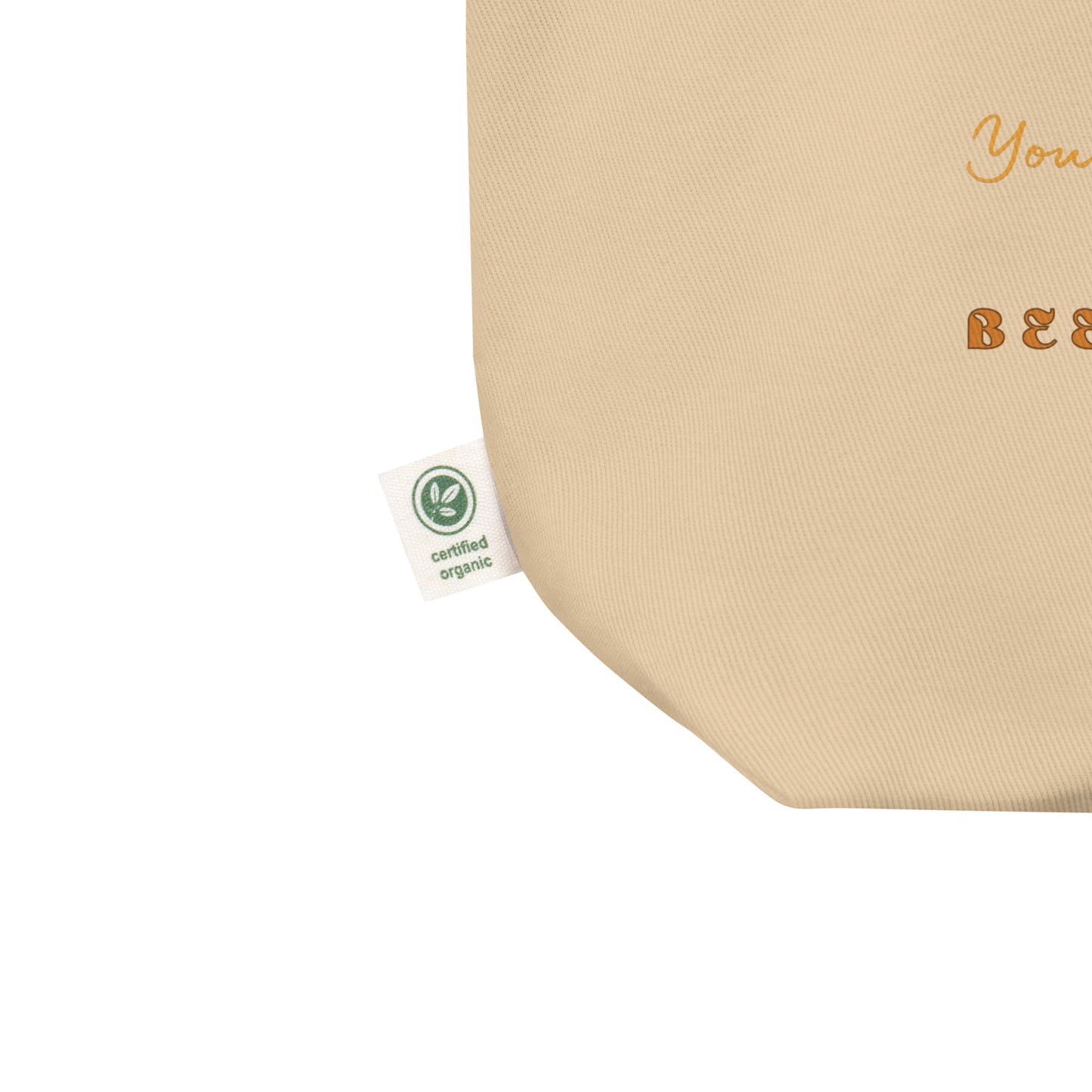 Beige eco tote bag with a green organic certification label on a white background. 
