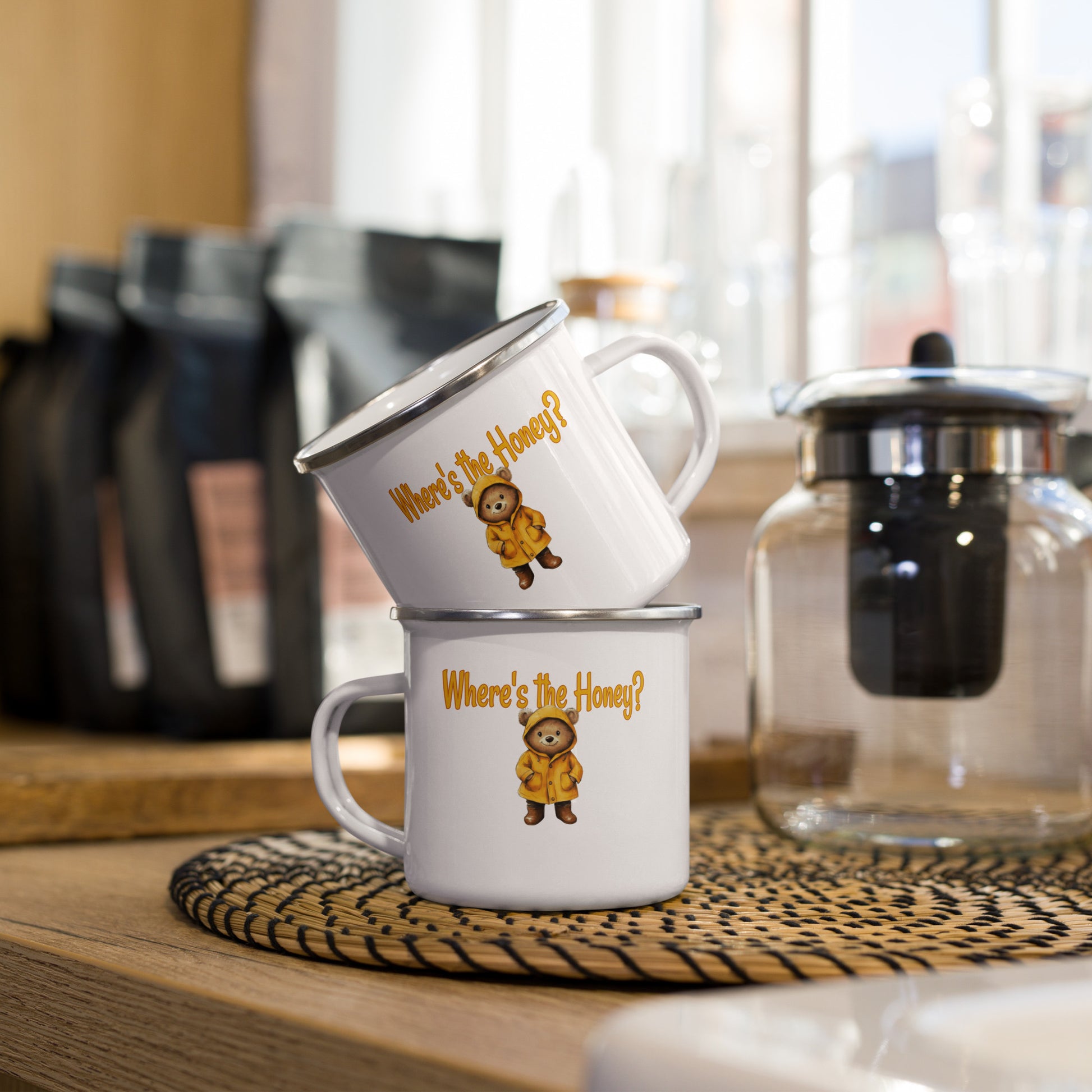 Two mugs stacked on a wooden surface with coffee-making equipment in the background.