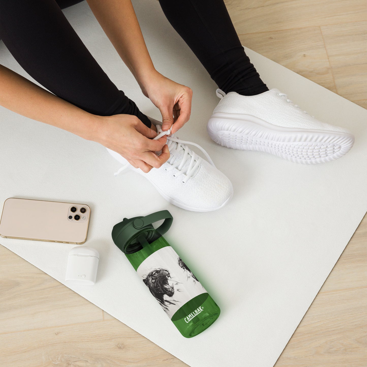 Person tying white sneakers next to a green and black reusable water bottle featuring a panther illustration and a flip straw lid.