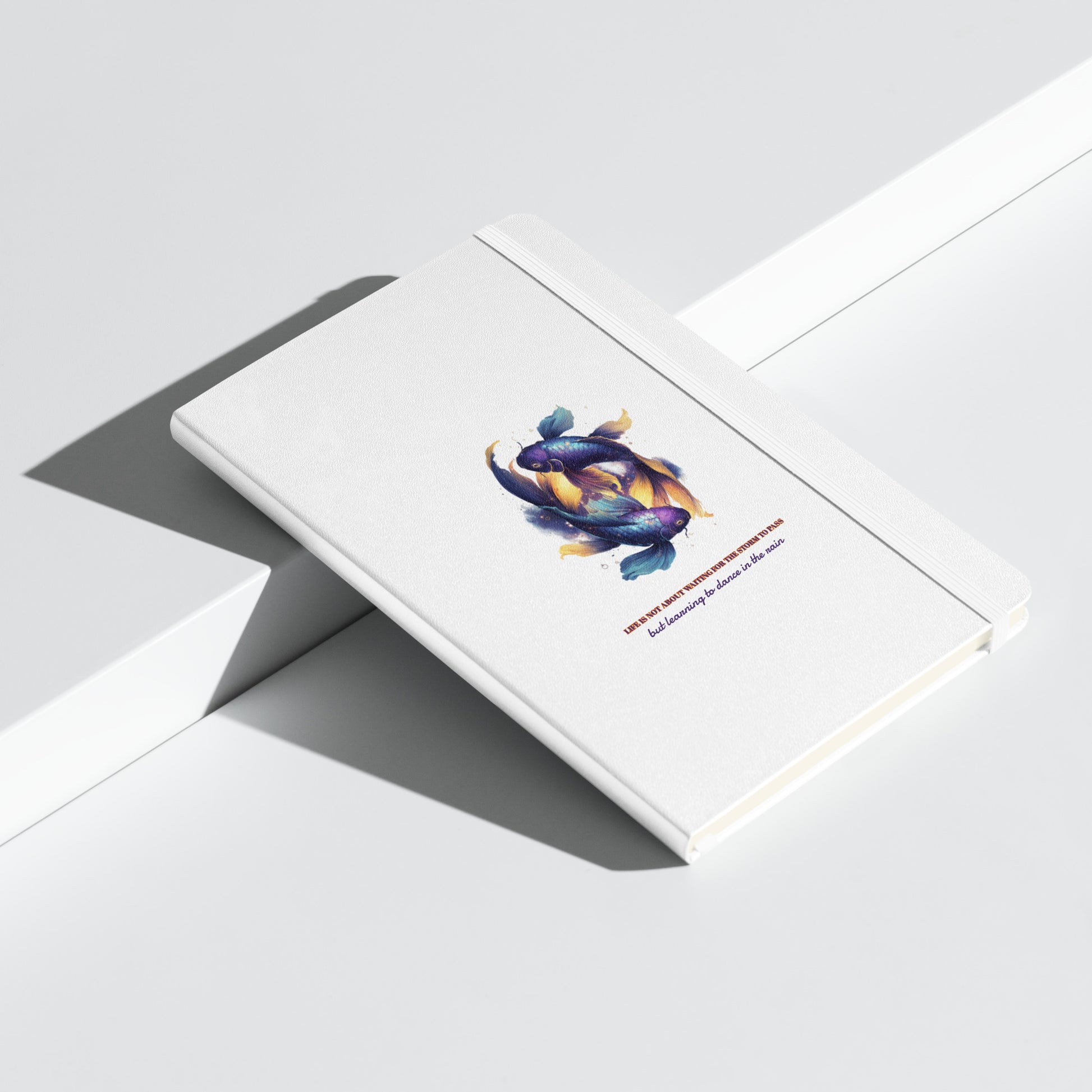 Person sitting by a rainy window in a cozy Scandi-style room, holding a white Sweet & Savage Pisces zodiac notebook featuring two illustrated fish and a motivational quote about dancing in the rain.