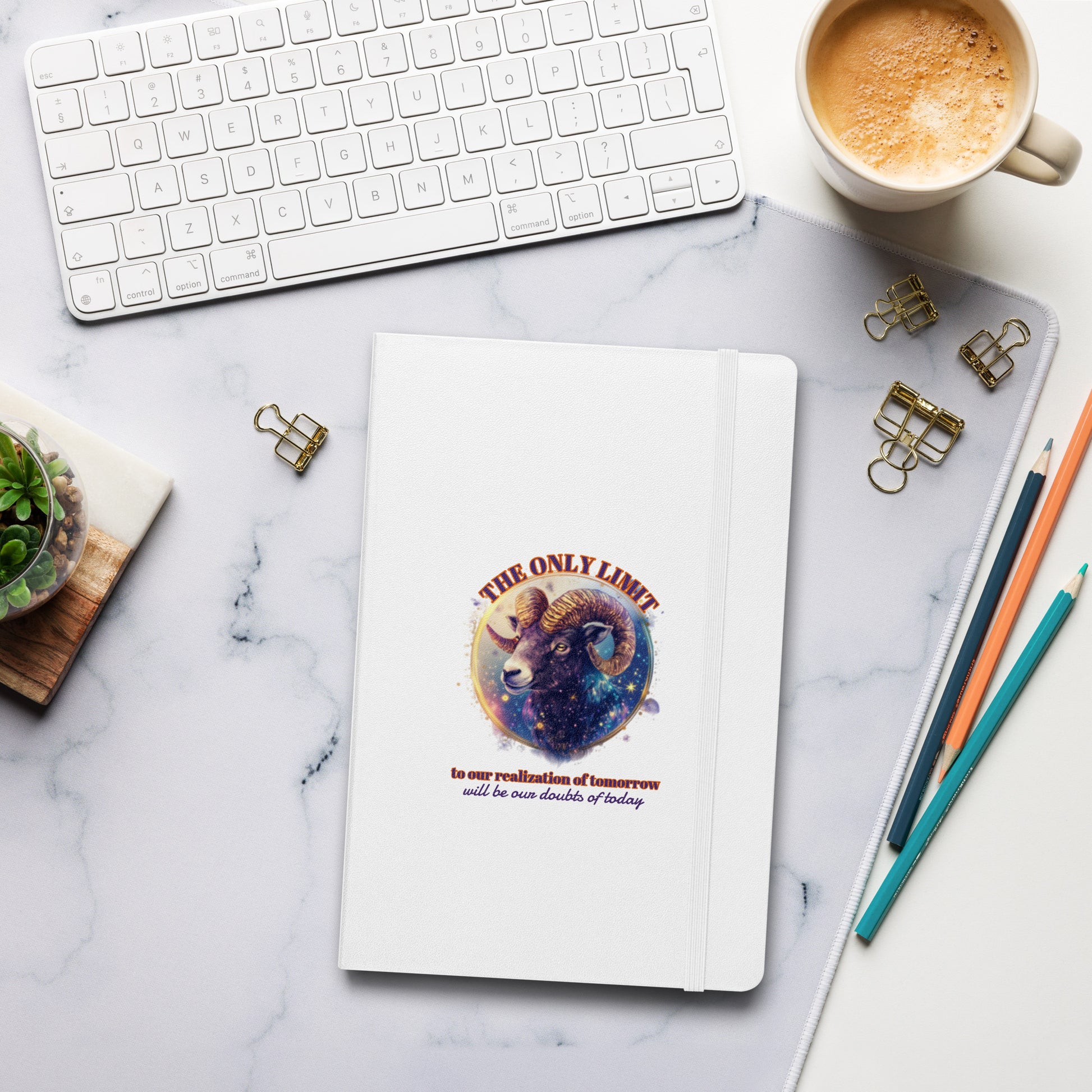 White hardcover notebook on a desk featuring a colorful, artistic Aries zodiac design by Sweet & Savage. 
