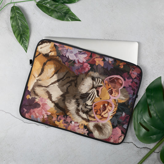 Artistic laptop sleeve featuring a bold tiger illustration wearing pink heart-shaped glasses, surrounded by purple and orange flowers, displayed as a product mockup on a light gray surface with green leaves.
