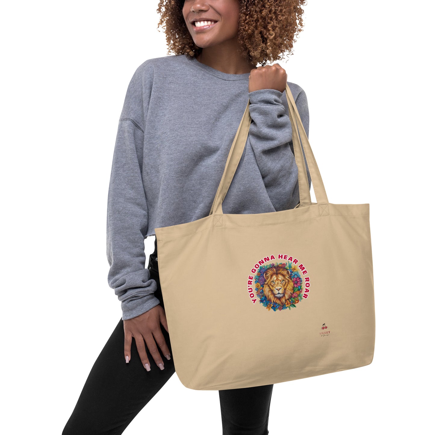 Woman carrying a large cream-colored organic tote bag with a colorful artistic lion design.
