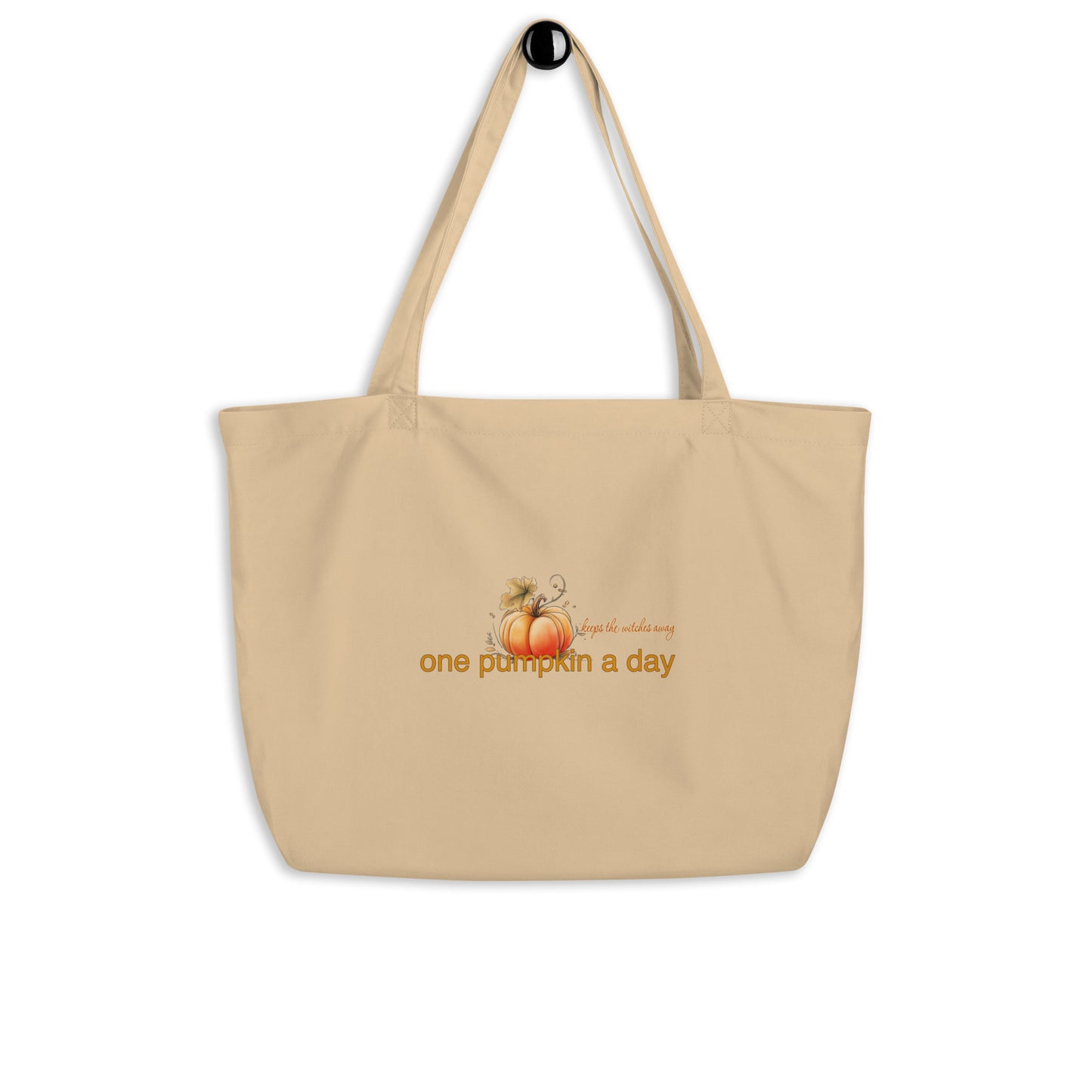 A beige canvas tote bag with two shoulder straps, featuring a graphic of a small orange pumpkin and the text 'One pumpkin a day, keeps the witches away' in orange on the front, shown against a plain white background.