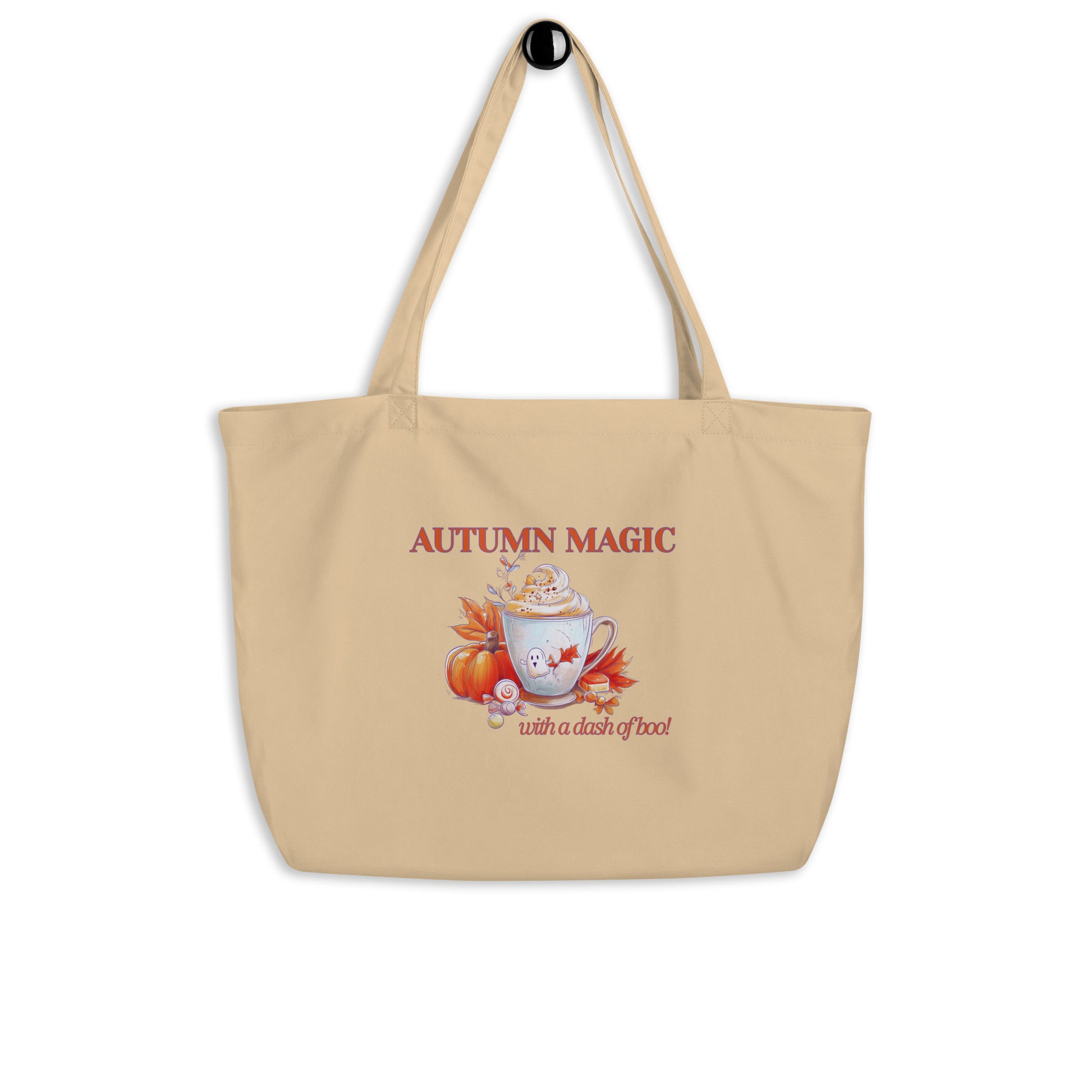 A beige canvas tote bag with a black top hook, featuring an autumn-themed graphic with the text 'AUTUMN MAGIC with a dash of boo' and an illustration of a mug, pumpkin, and fall leaves.