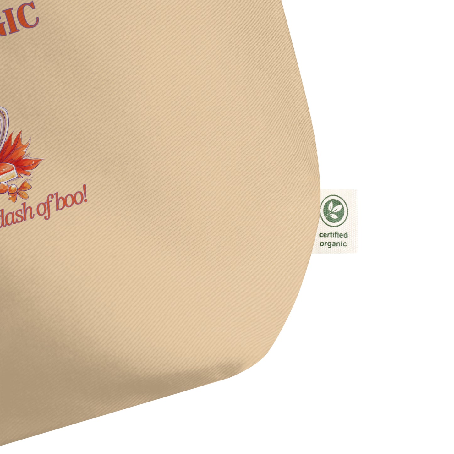 Close-up of a beige canvas tote bag corner with partial printed text and a small green Certified Organic tag on the side, against a white background.
