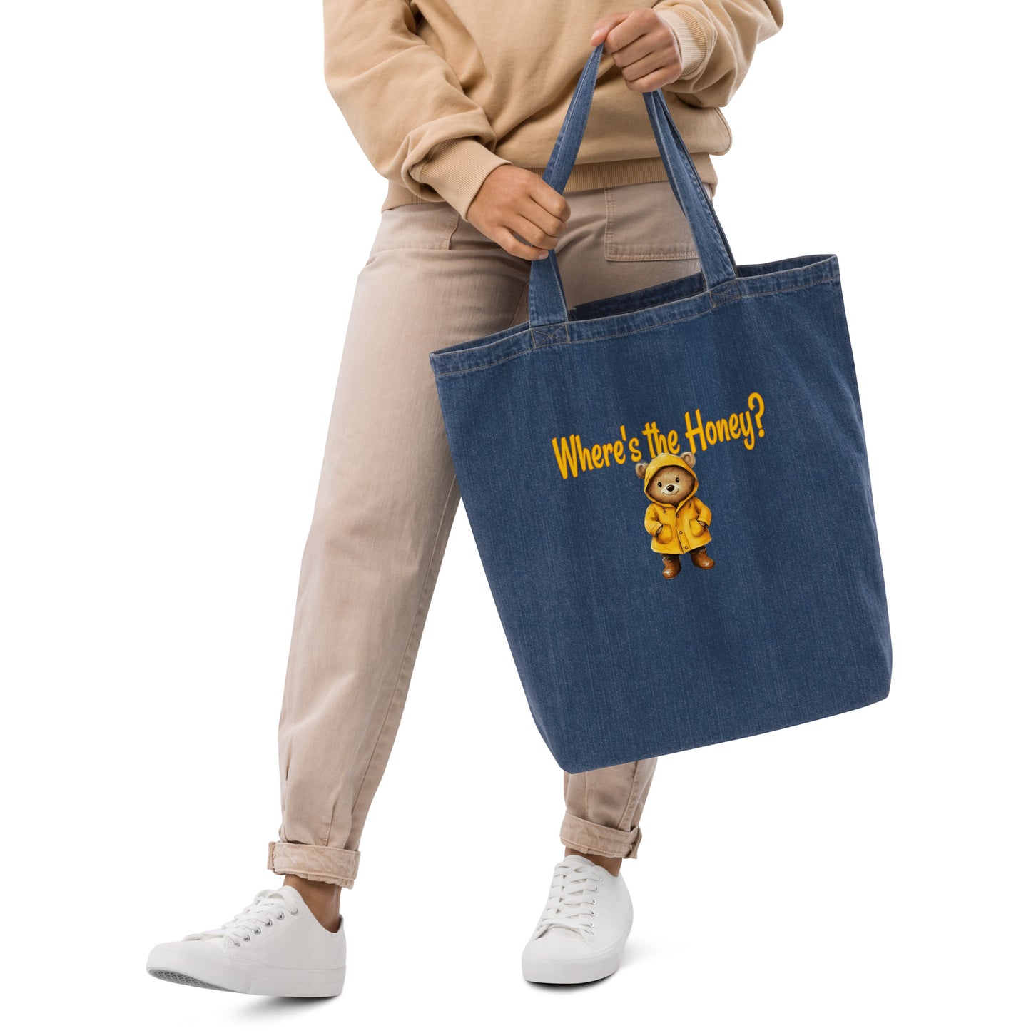 Person holding a blue tote bag with a cartoon bear and text on a white background. 