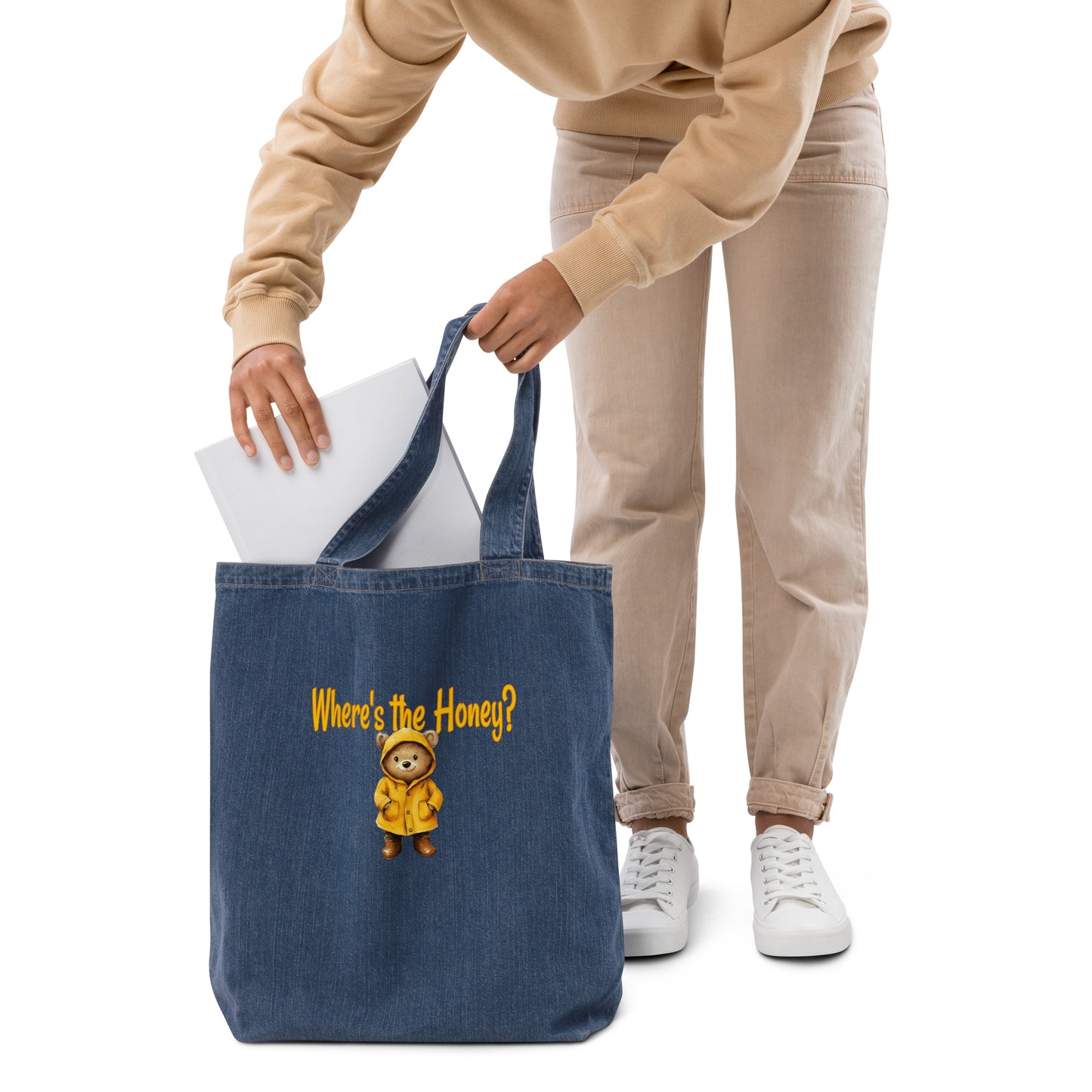 Person holding an organic denim tote bag with a bear design and text on a white background. 
