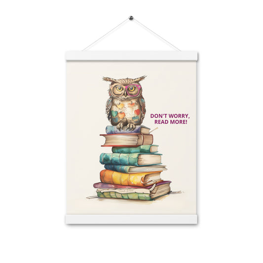 Whimsical illustration of an owl sitting on a tall stack of colorful books with the text "Don't Worry, Read More!". The poster is displayed with natural light-wood magnetic hangers and a hanging string.