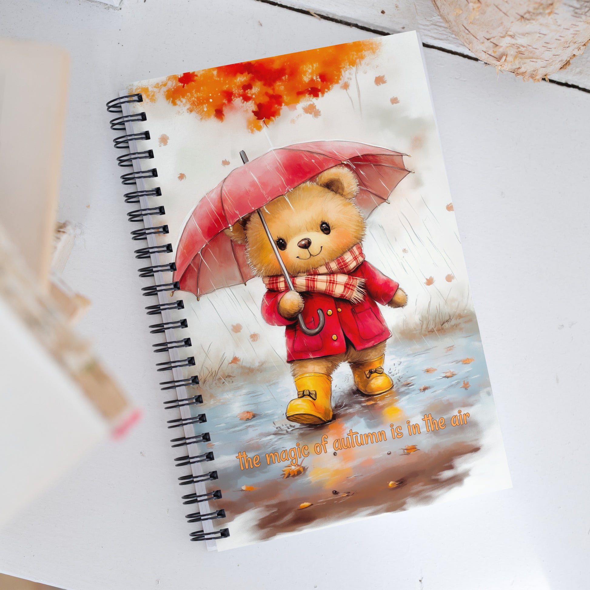 Notebook with a teddy bear design on the cover, featuring a red umbrella and coat.