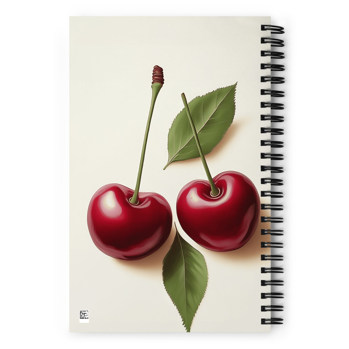Spiral notebook with a design of two red cherries and two green leaves on a beige background. 