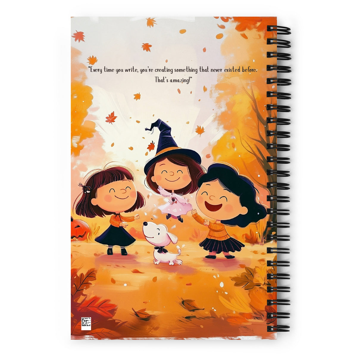 A spiral-bound notebook with a warm autumn-themed cover illustration. The cover features three smiling girls in witch costumes and a small white dog among falling leaves, with a quote at the top.