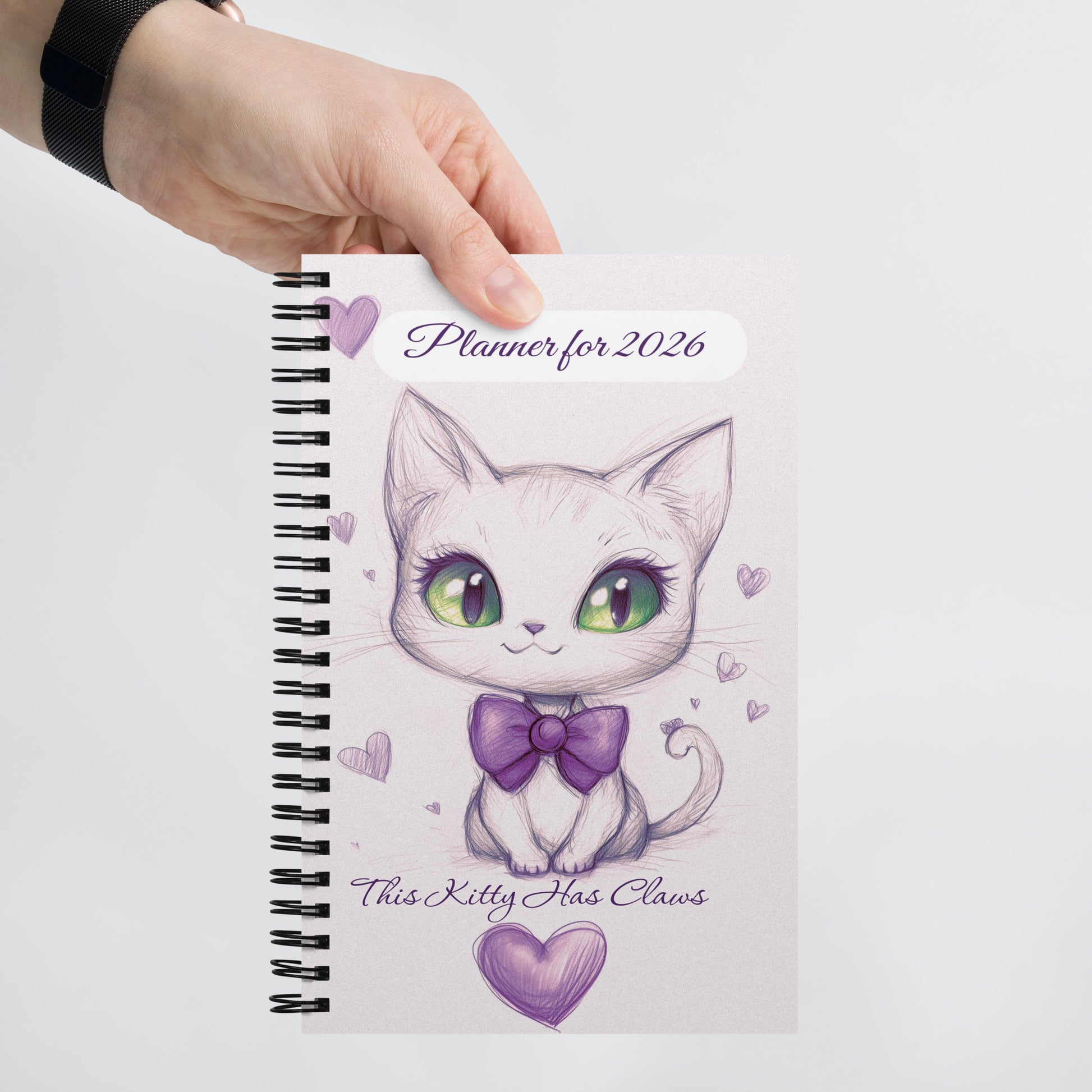 Planner for 2026 with a cute cat illustration that is surrounded by purple hearts and text on a white background. 