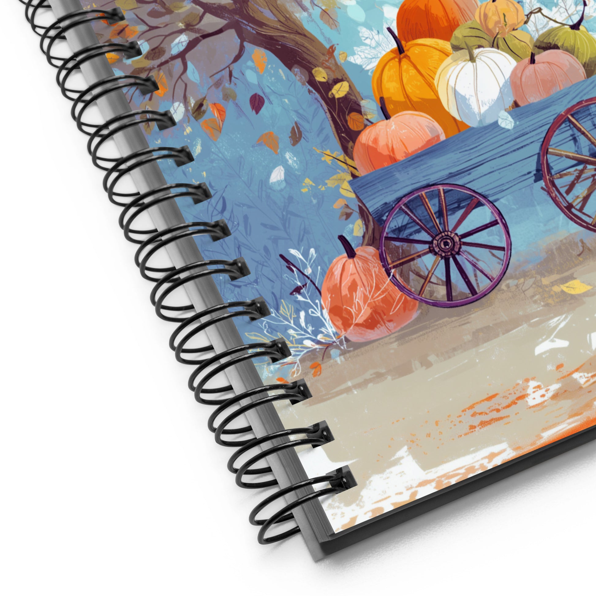 Spiral notebook with a spiral binding featuring an autumn design with pumpkins and a wagon.
