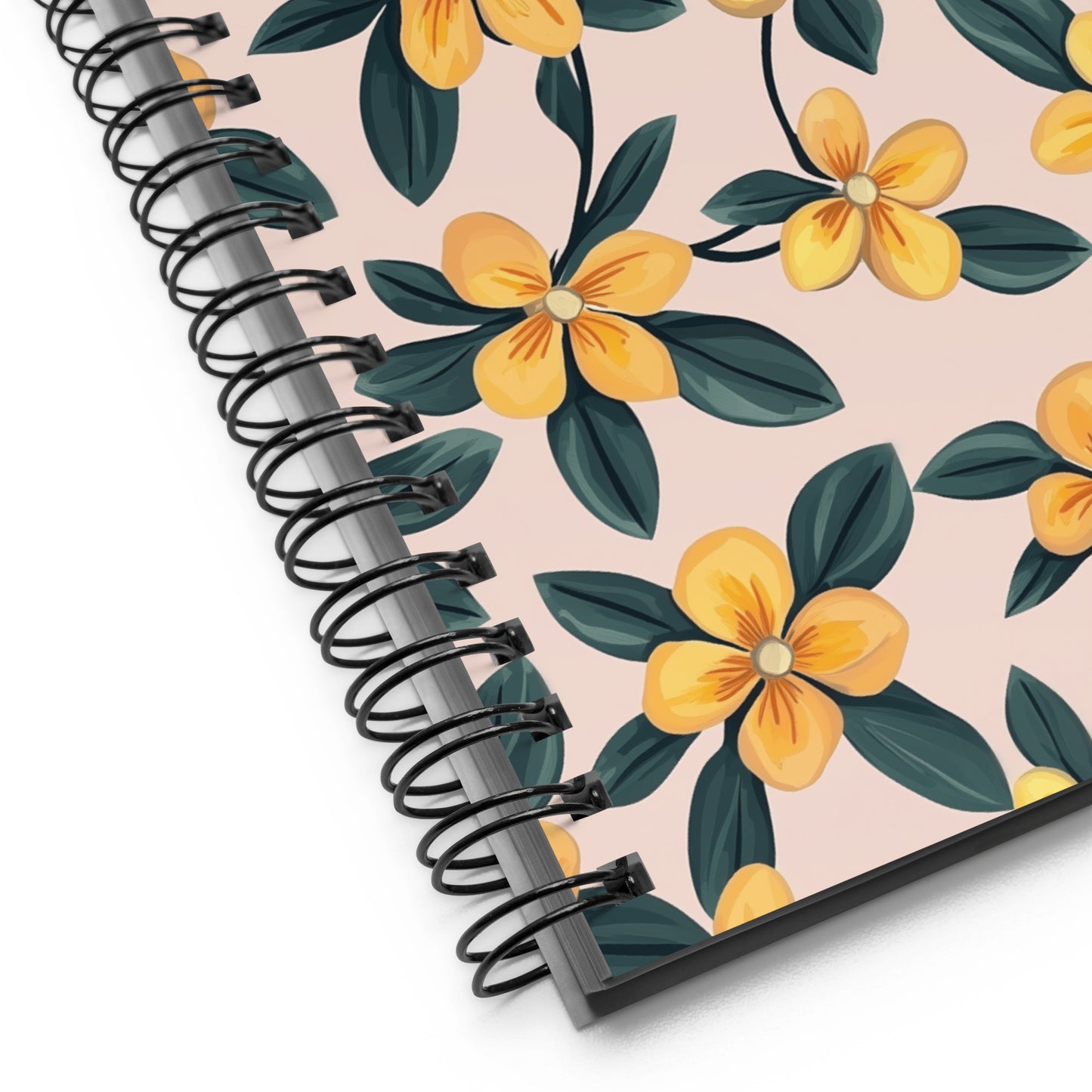 Close up of a spiral-bound notebook with yellow Periwinkles design on a beige background. 