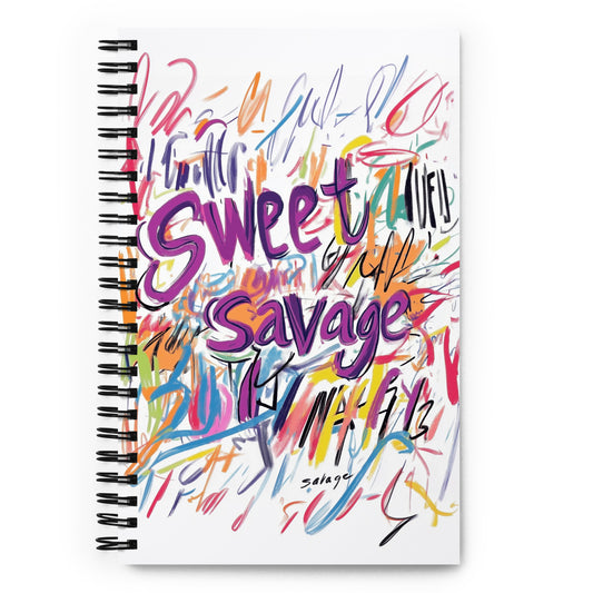 Spiral notebook with a white background featuring vibrant purple and multi-colored "Sweet Savage" artistic typography and expressive scribbles.