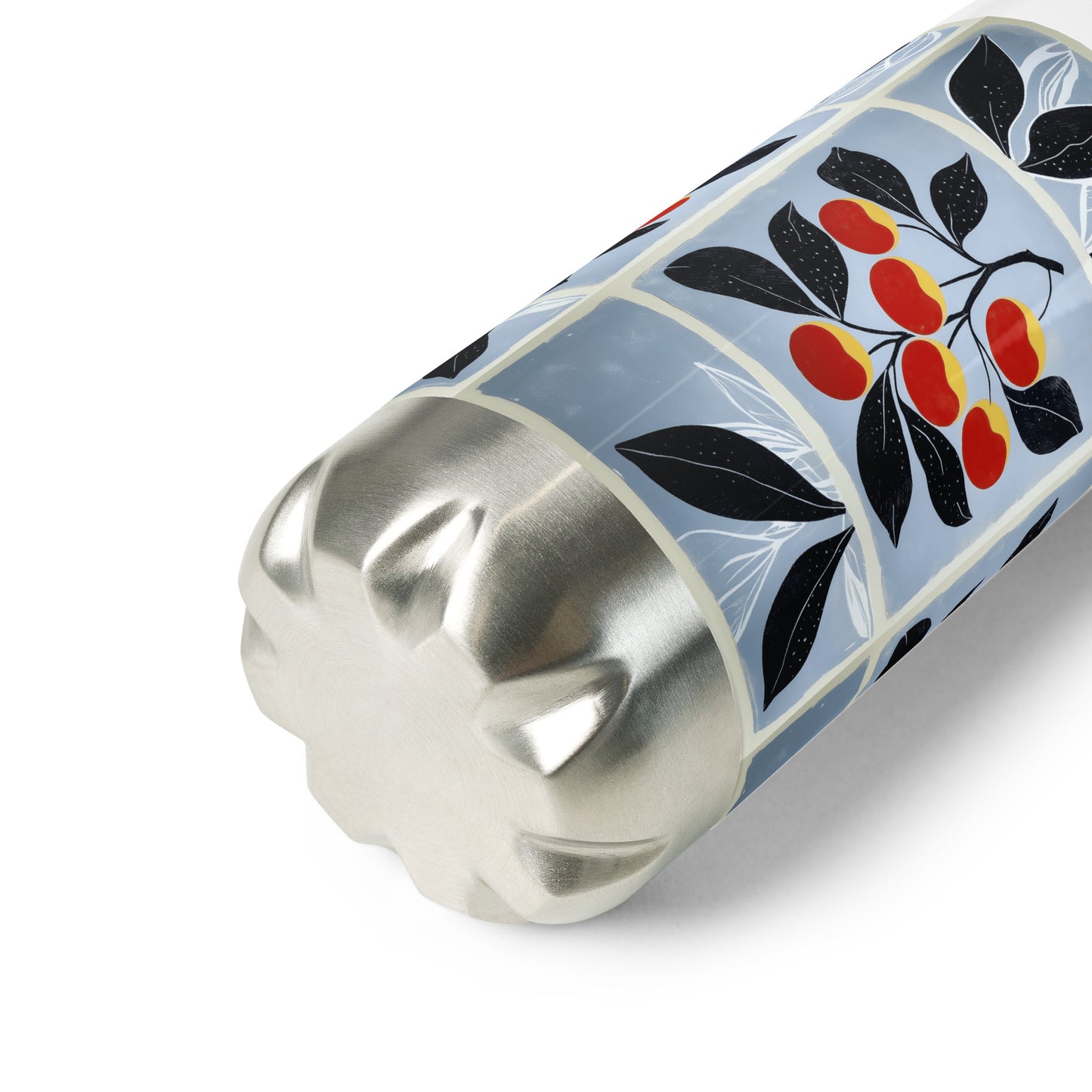 A close-up of a cylindrical metal container with a silver fluted base and a decorative wrap featuring black leaves and red-cherries on a pale blue background.