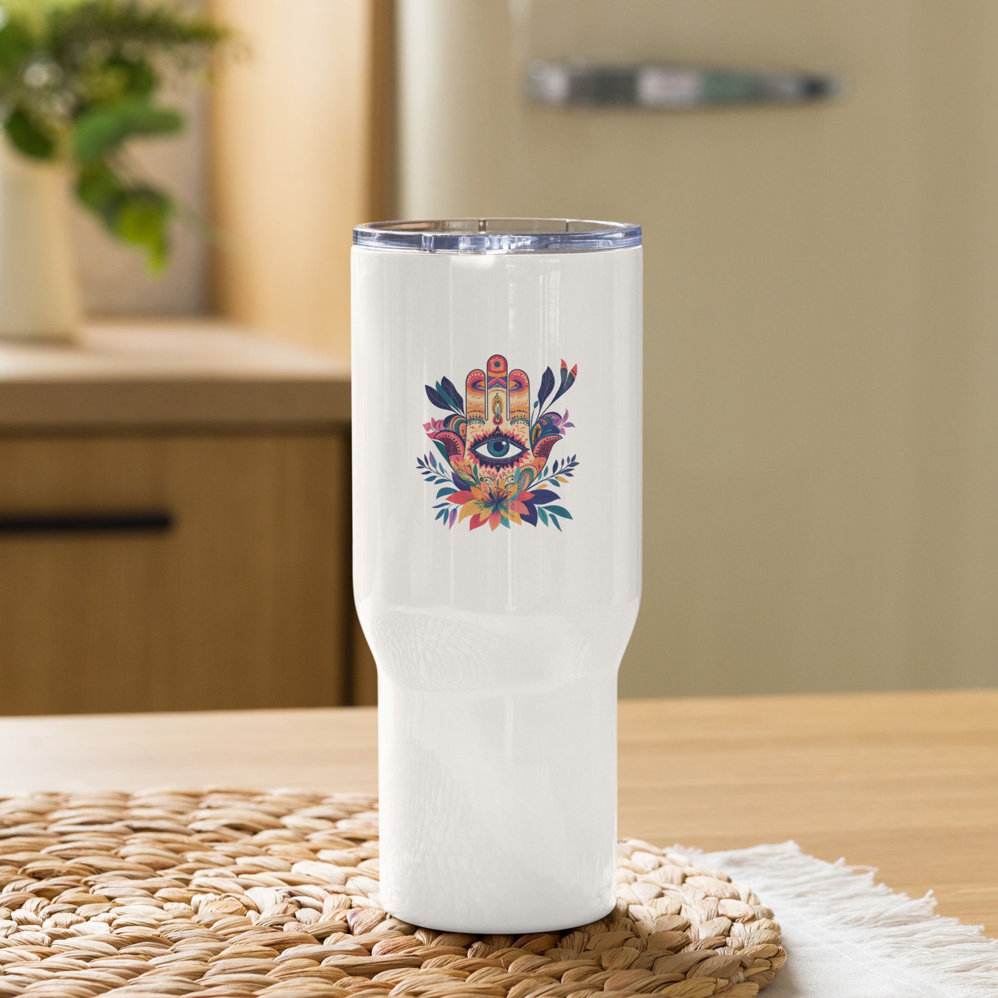 Large white travel mug with a handle featuring a colorful Hamsa hand art print on a table.