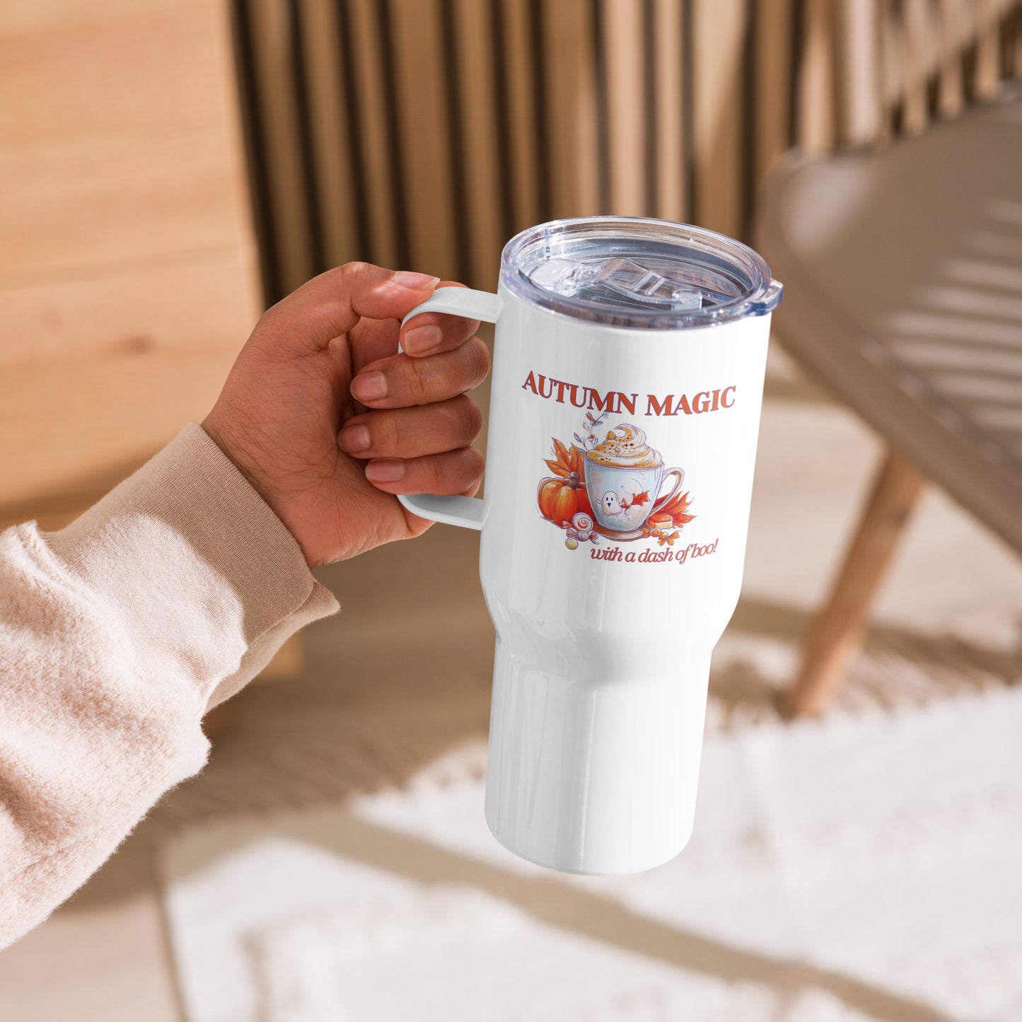 Hand holding a white tumbler with illustration of a mug with a cute ghost, pumpkin, orange leaves and words 'Autumn Magic and a dash of boo!' by Sweet & Savage. 