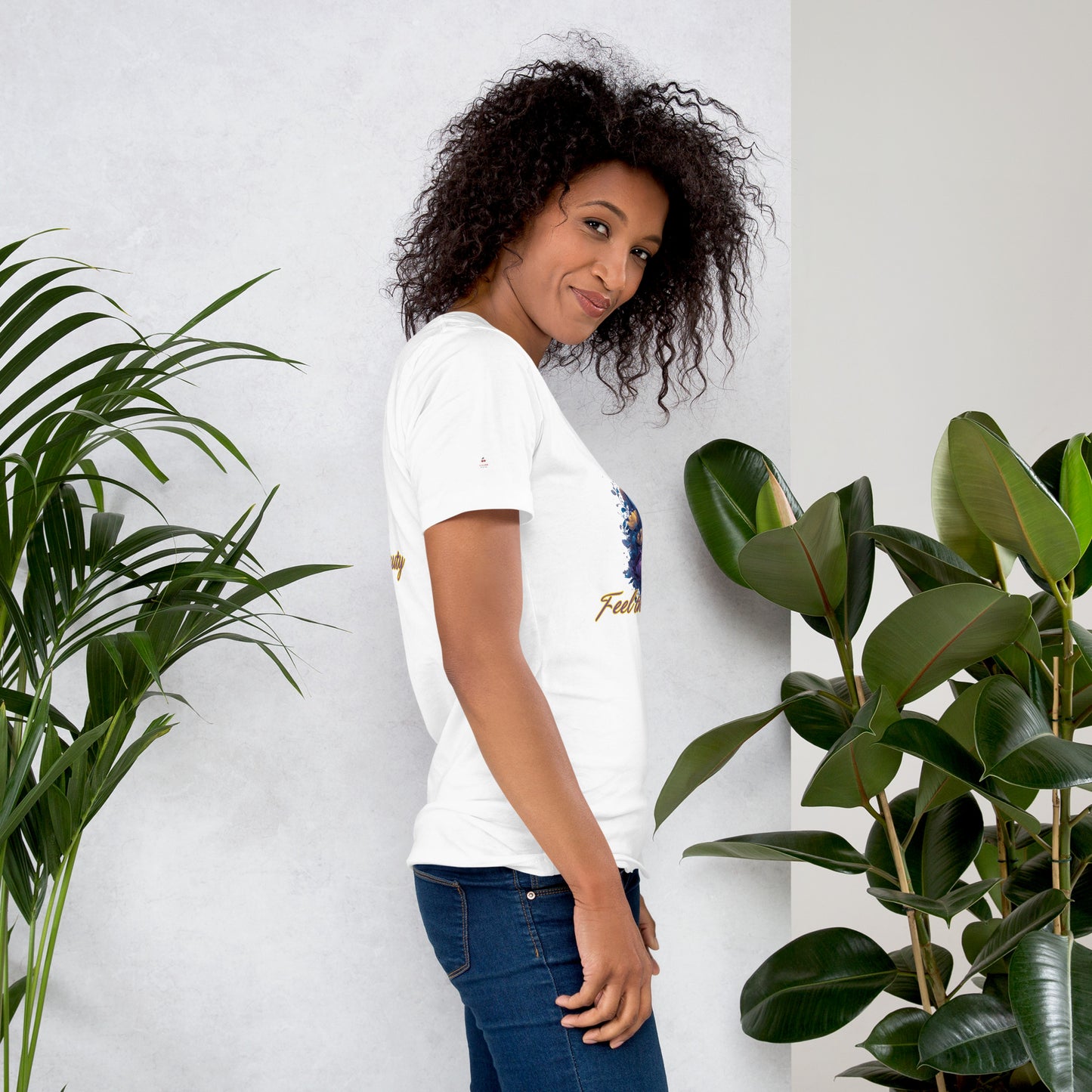 Woman wearing a white t-shirt with a cherry logo, standing between two potted plants against a light gray wall.
